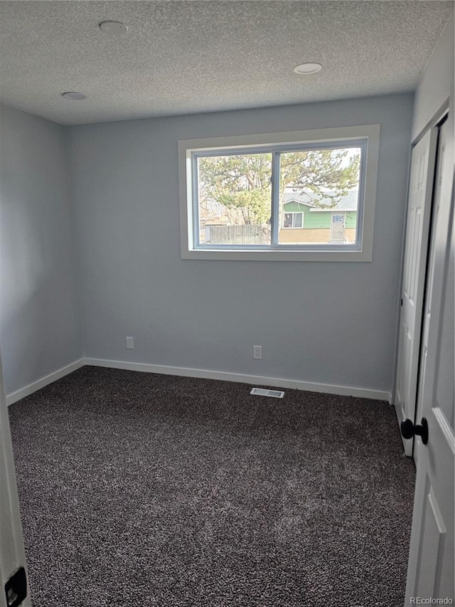 carpeted empty room featuring a healthy amount of sunlight and a textured ceiling