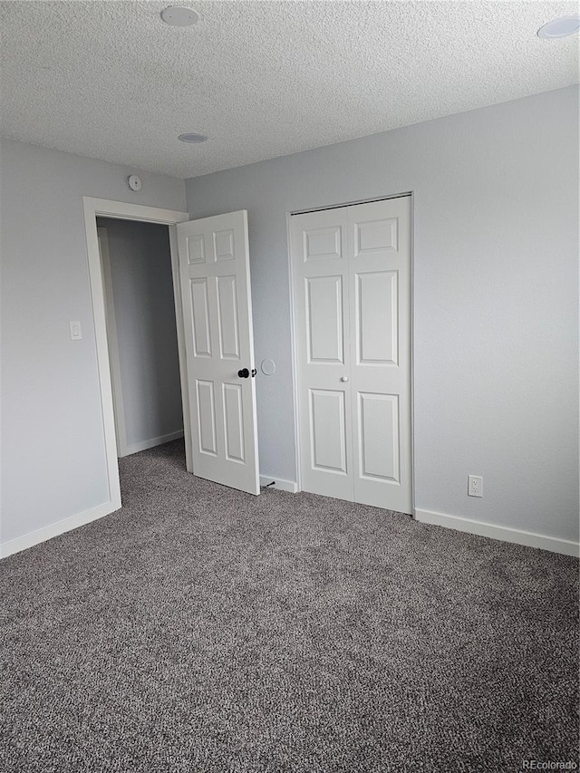 unfurnished bedroom featuring dark colored carpet, a textured ceiling, and a closet