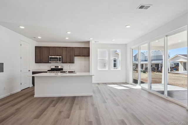 kitchen featuring stainless steel appliances, light wood-type flooring, dark brown cabinetry, and visible vents