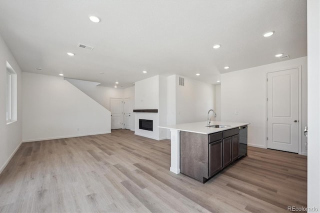 kitchen featuring light wood finished floors, black dishwasher, visible vents, and a sink