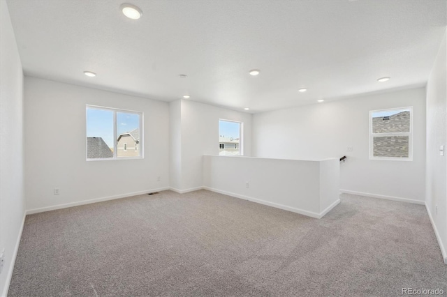 spare room featuring light colored carpet, baseboards, and recessed lighting