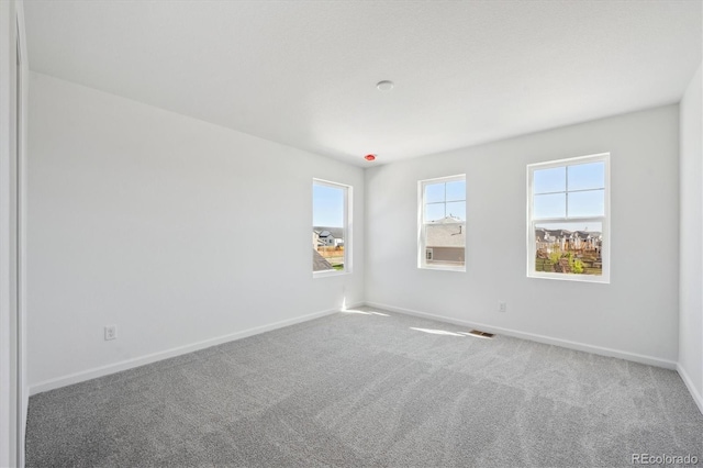 carpeted empty room with plenty of natural light and baseboards