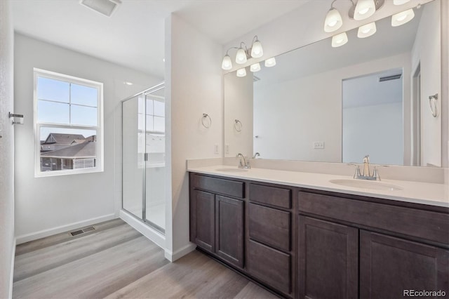full bathroom with a sink, a shower stall, visible vents, and wood finished floors