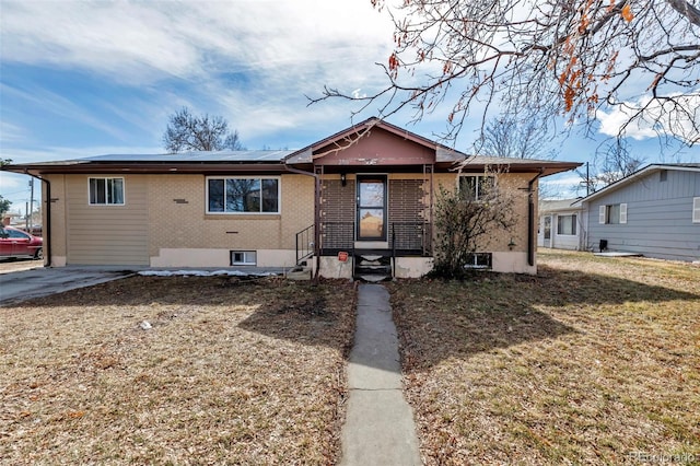 view of front of home featuring entry steps, a front yard, roof mounted solar panels, and brick siding