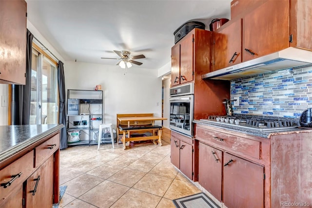 kitchen featuring ceiling fan, light tile patterned flooring, under cabinet range hood, appliances with stainless steel finishes, and backsplash