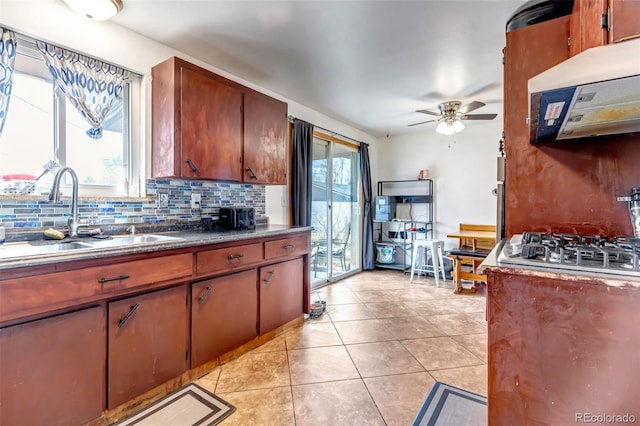 kitchen with light tile patterned floors, a ceiling fan, a sink, ventilation hood, and backsplash