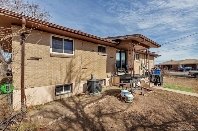 back of house featuring cooling unit and brick siding