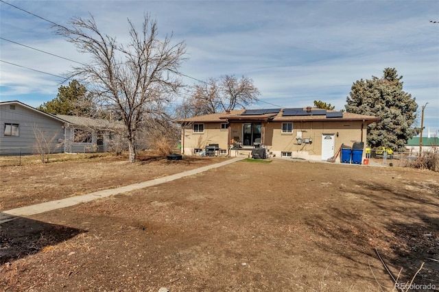 back of property featuring fence and solar panels