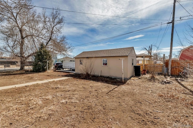 view of side of property featuring roof with shingles, fence, and stucco siding