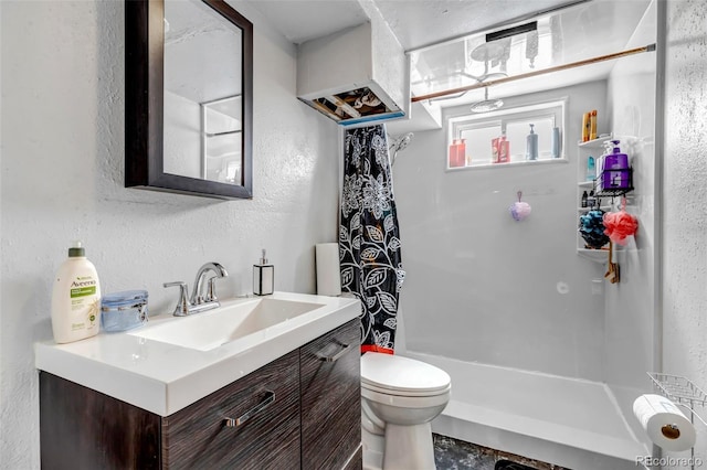 bathroom featuring a textured wall, vanity, toilet, and walk in shower