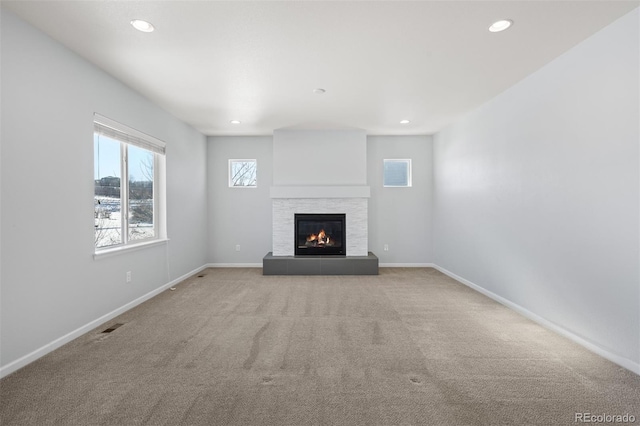 unfurnished living room with a tile fireplace and light carpet