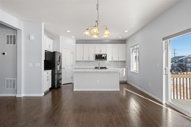 kitchen featuring stainless steel appliances, a center island with sink, white cabinetry, and hanging light fixtures