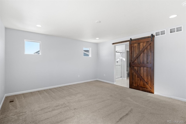 carpeted empty room featuring a barn door