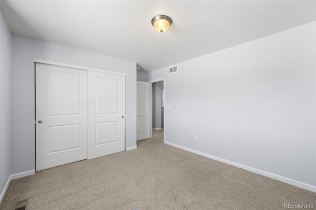 unfurnished bedroom with light colored carpet and a closet