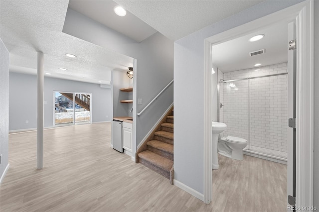 staircase with a textured ceiling and hardwood / wood-style floors