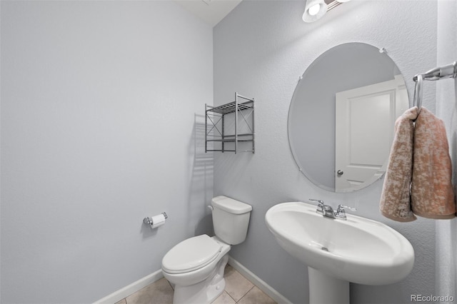 bathroom with toilet, tile patterned flooring, and sink