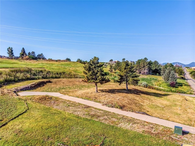 surrounding community with a mountain view and a lawn