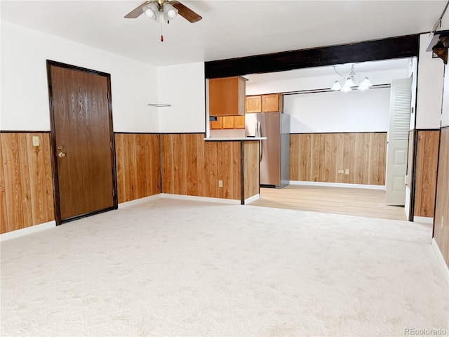 390 Zang St Unit 5-102, Lakewood, CO 80228 - unfurnished room featuring beam ceiling, ceiling fan with notable chandelier, light carpet, and wood walls