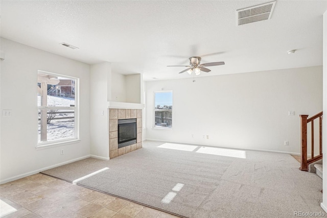 unfurnished living room with a fireplace, a textured ceiling, light colored carpet, and ceiling fan