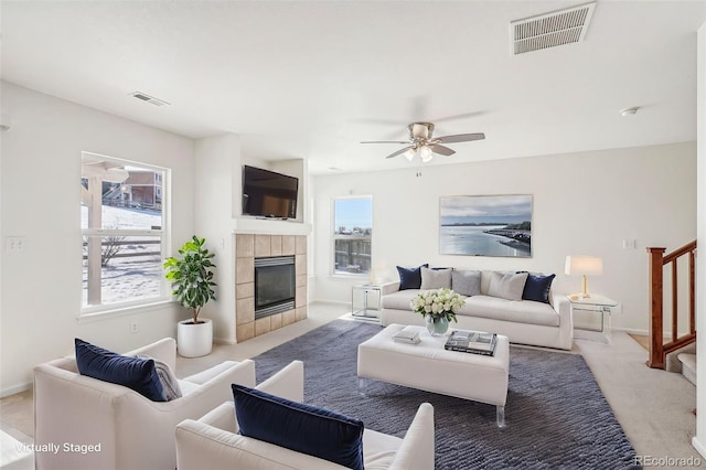 carpeted living room featuring ceiling fan and a fireplace