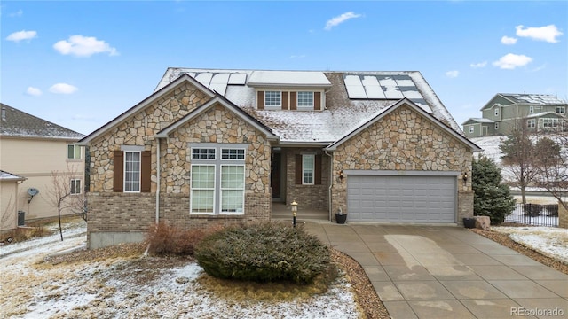 view of front of property featuring driveway, fence, an attached garage, brick siding, and solar panels