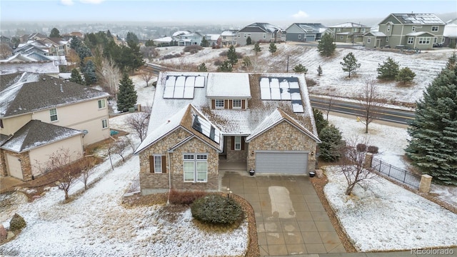 view of front of home with stone siding, roof mounted solar panels, fence, a residential view, and concrete driveway