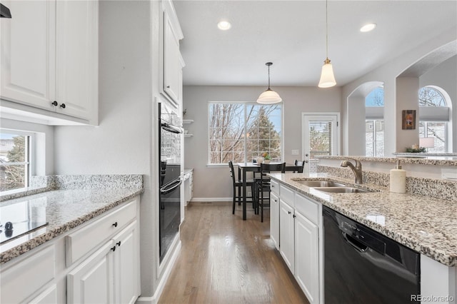 kitchen featuring a sink, wood finished floors, black appliances, and white cabinets