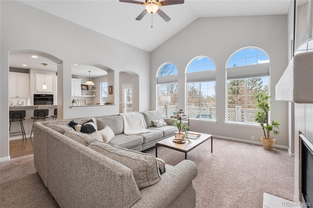 living room featuring baseboards, high vaulted ceiling, a ceiling fan, and carpet