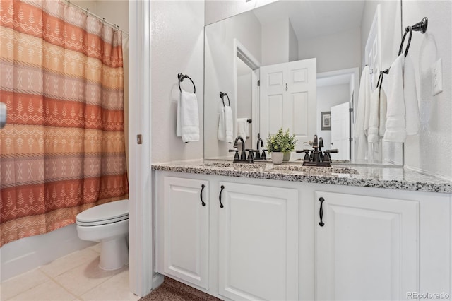 bathroom with tile patterned floors, toilet, double vanity, and a sink