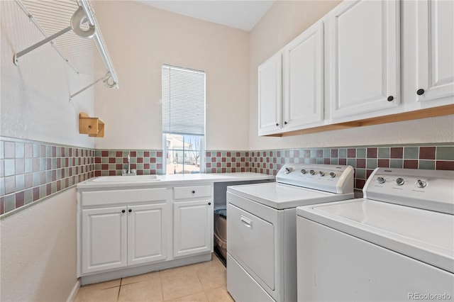 washroom with a sink, cabinet space, tile walls, light tile patterned flooring, and washing machine and clothes dryer