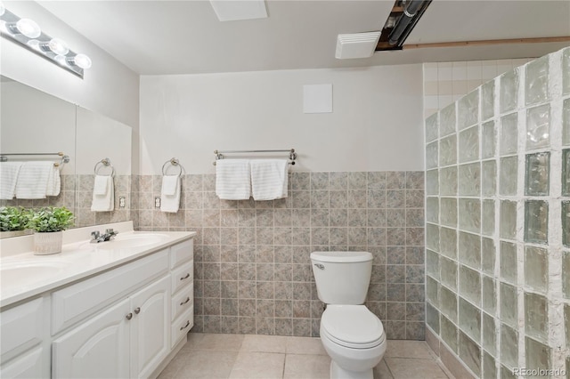 full bathroom featuring tile patterned flooring, tile walls, toilet, and a sink