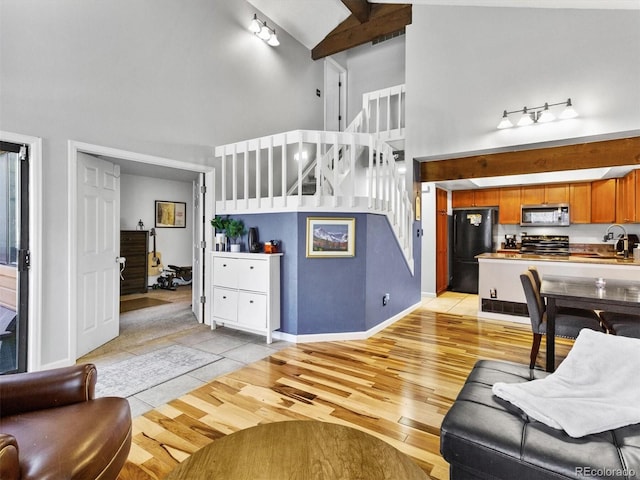 living room with sink, high vaulted ceiling, beam ceiling, and light hardwood / wood-style flooring