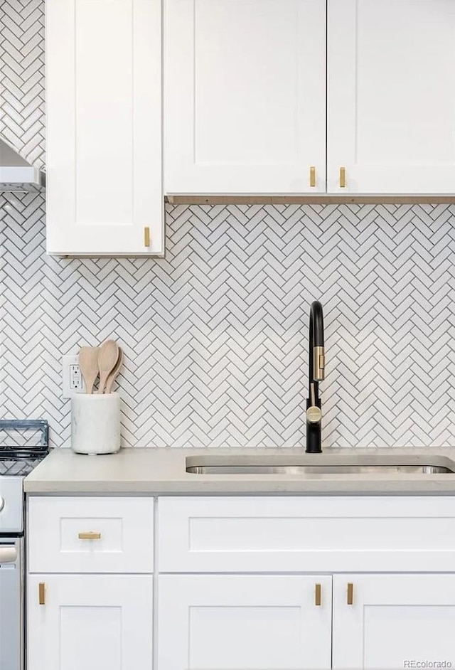 9265 Newton St, Westminster, CO 80031 - kitchen with white range oven, light countertops, white cabinets, and decorative backsplash