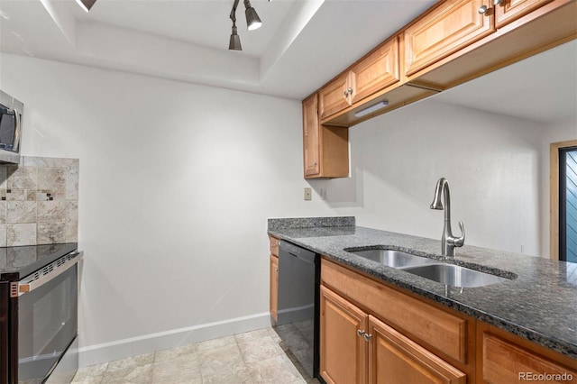 kitchen featuring dishwasher, dark stone countertops, sink, a tray ceiling, and stove