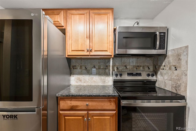 kitchen featuring stainless steel appliances, dark stone countertops, and backsplash