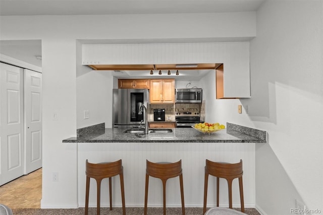 kitchen featuring a kitchen bar, sink, backsplash, and stainless steel appliances