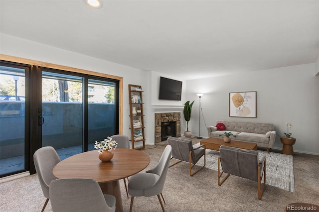 carpeted dining room featuring a stone fireplace