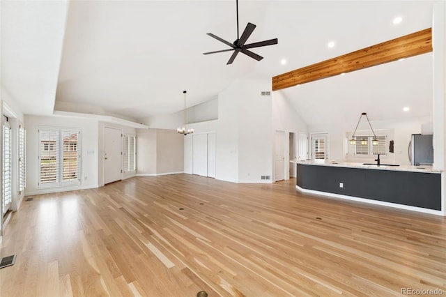 1904 S Union Pl, Lakewood, CO 80228 - unfurnished living room with a sink, a ceiling fan, a chandelier, light wood-style floors, and beam ceiling
