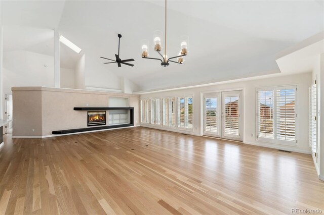 1904 S Union Pl, Lakewood, CO 80228 - unfurnished living room with a chandelier, light wood-style floors, a glass covered fireplace, high vaulted ceiling, and baseboards