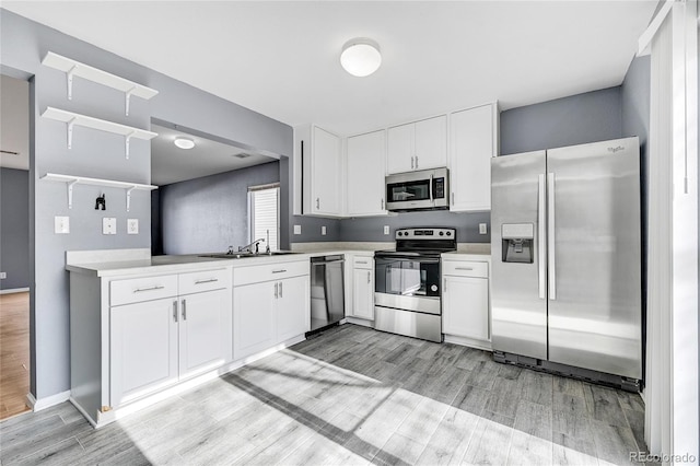 kitchen with stainless steel appliances, sink, white cabinets, and light wood-type flooring