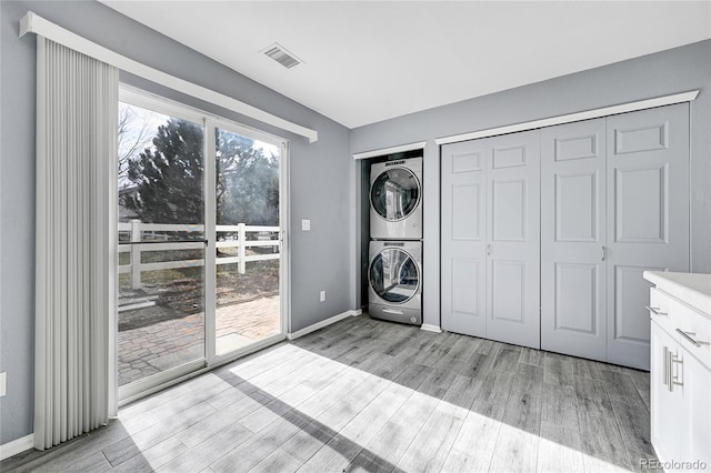 laundry room featuring stacked washer / dryer and light wood-type flooring