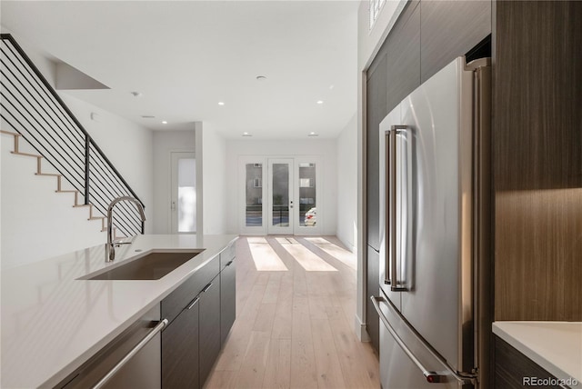 kitchen featuring appliances with stainless steel finishes, light wood-type flooring, french doors, and sink