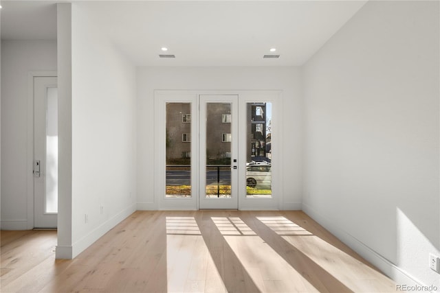 spare room with french doors and light hardwood / wood-style flooring