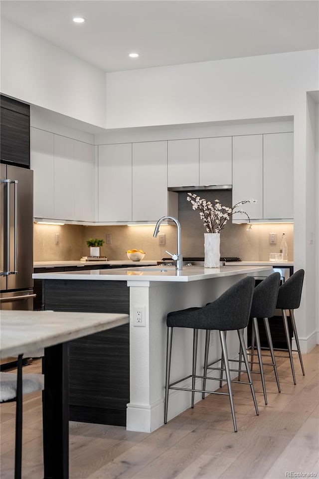 kitchen with light countertops, high quality fridge, a breakfast bar area, and modern cabinets