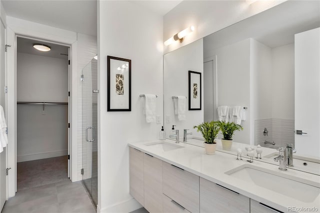 full bathroom with double vanity, a stall shower, a sink, and baseboards