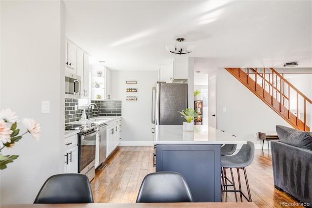 kitchen with tasteful backsplash, stainless steel appliances, a kitchen breakfast bar, and white cabinets