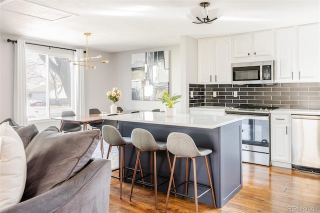 kitchen featuring white cabinetry, appliances with stainless steel finishes, a center island, and hanging light fixtures