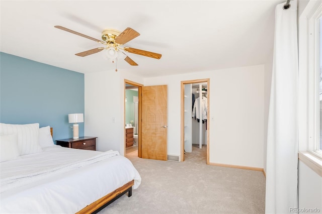 carpeted bedroom featuring a spacious closet, a closet, ceiling fan, and ensuite bathroom