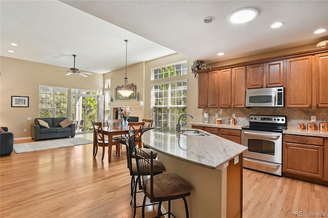 23285 Chapel Hill Ln, Parker, CO 80138 - kitchen featuring appliances with stainless steel finishes, light wood-style floors, open floor plan, tasteful backsplash, and recessed lighting