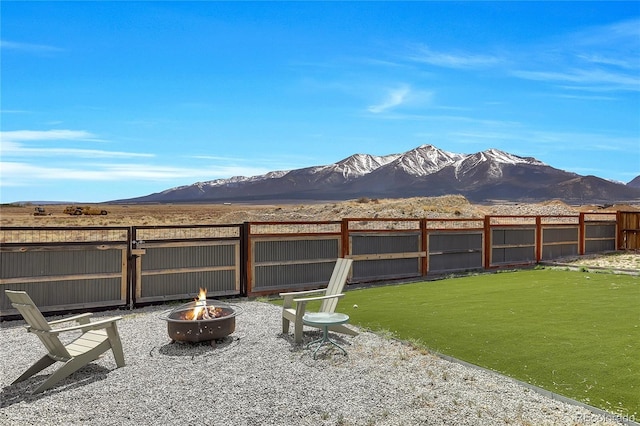 view of yard with an outdoor fire pit, a mountain view, and fence